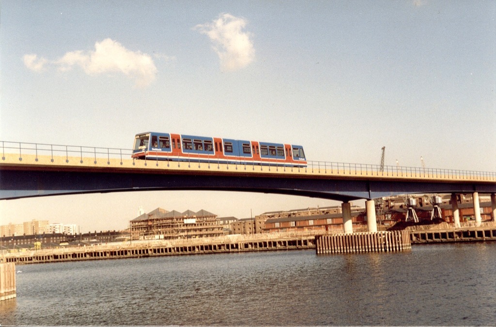 ▲第一代輕鐵列車駛過跨越西印度船塢的大橋（1987年9月）（來源：維基百科）